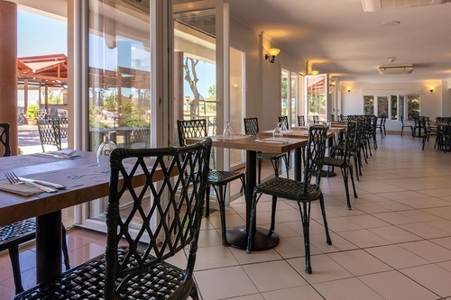 Pato Rojo Hotel's bright restaurant, tables set for dining, with views of the outdoor terrace in Punta Umbria.