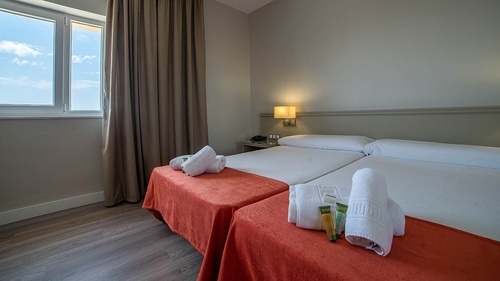 Pato Rojo Hotel twin room with comfortable beds, toiletries, and a bright window view in Punta Umbria, Huelva.