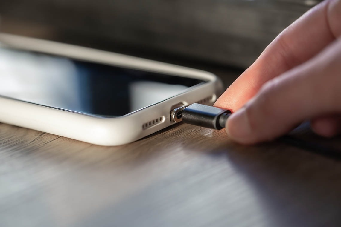 Charging phone on a wooden table, offering Pato: Corporativa guests essential connectivity.