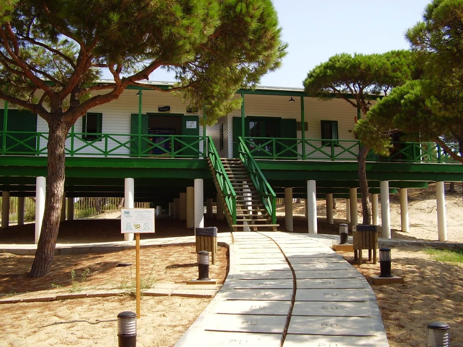 Hotel de praia Pato, construção corporativa elevada com varanda verde e pinheiros.