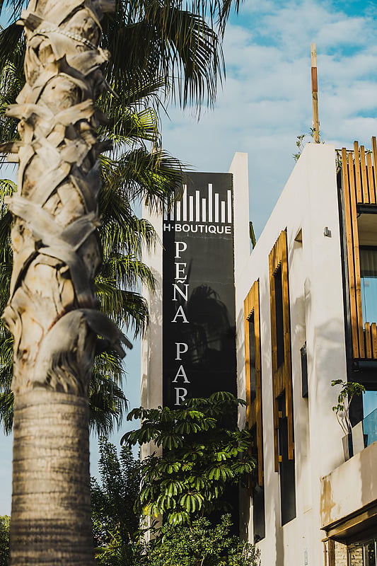 Pena Parda: Fachada boutique H-PENA PAR, estilo moderno y palmeras.