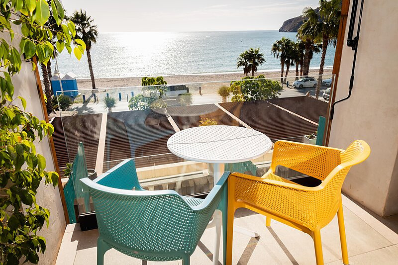 Terraza de una habitación del H. Boutique Peña Parda con mesa, sillas y vistas a la playa y al mar.