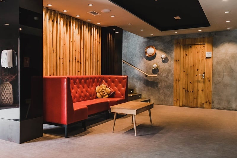 una habitación con un sofá rojo y una mesa de madera