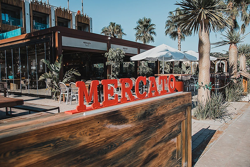 Terraza exterior del Restaurante Mercato del H. Boutique Peña Parda, con las letras rojas Mercato y palmeras.
