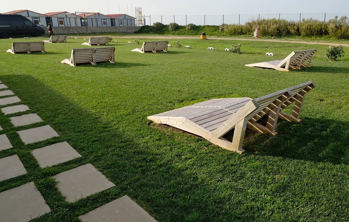 a row of wooden chairs in a lush green field