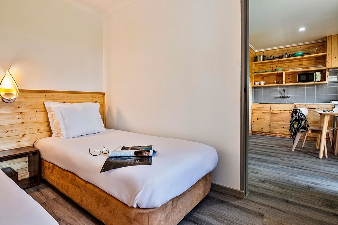 uma cama com duas almofadas brancas e uma cabeceira de madeira