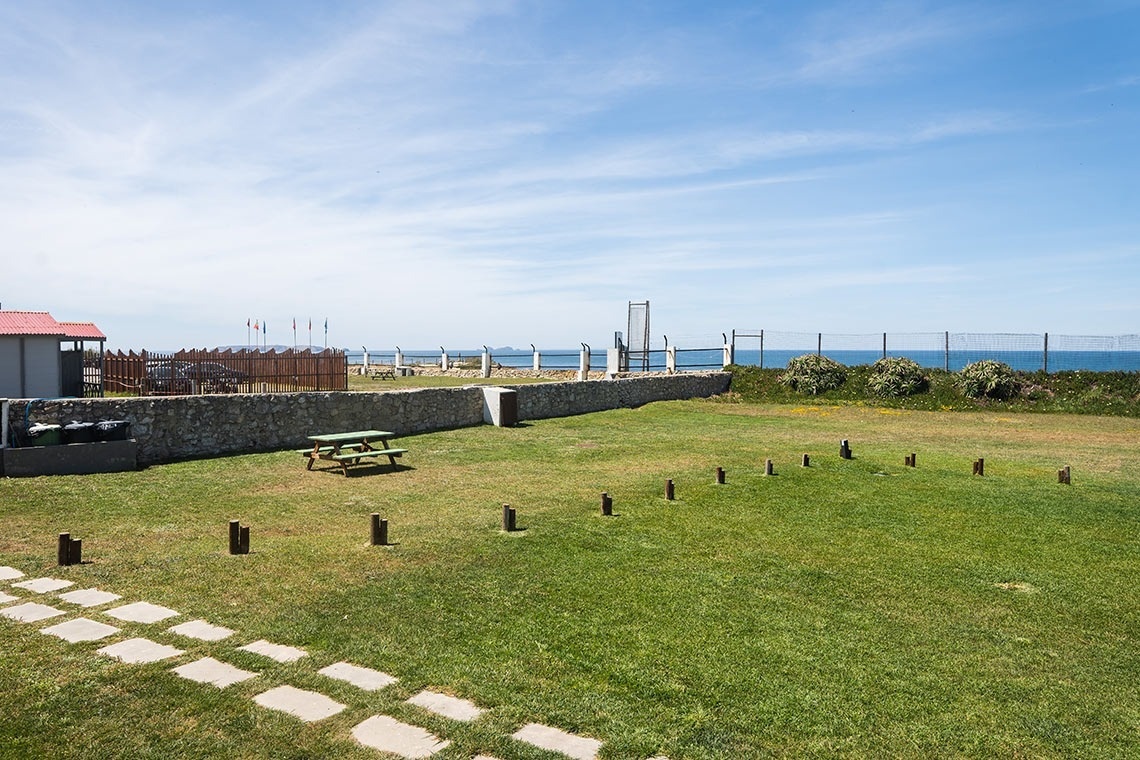 uma área gramada com uma mesa de piquenique em frente ao oceano