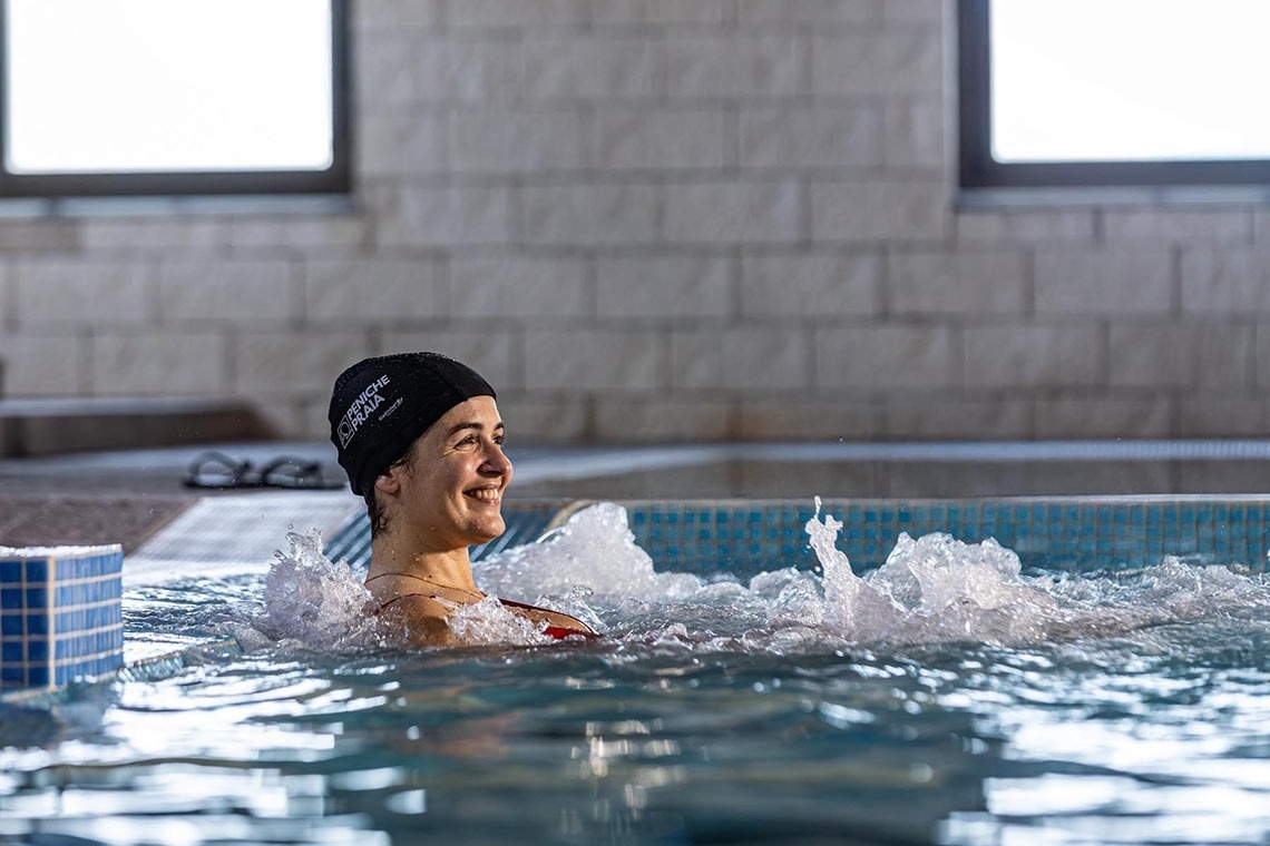 a woman in a swimming pool wearing a swim cap that says aquafina