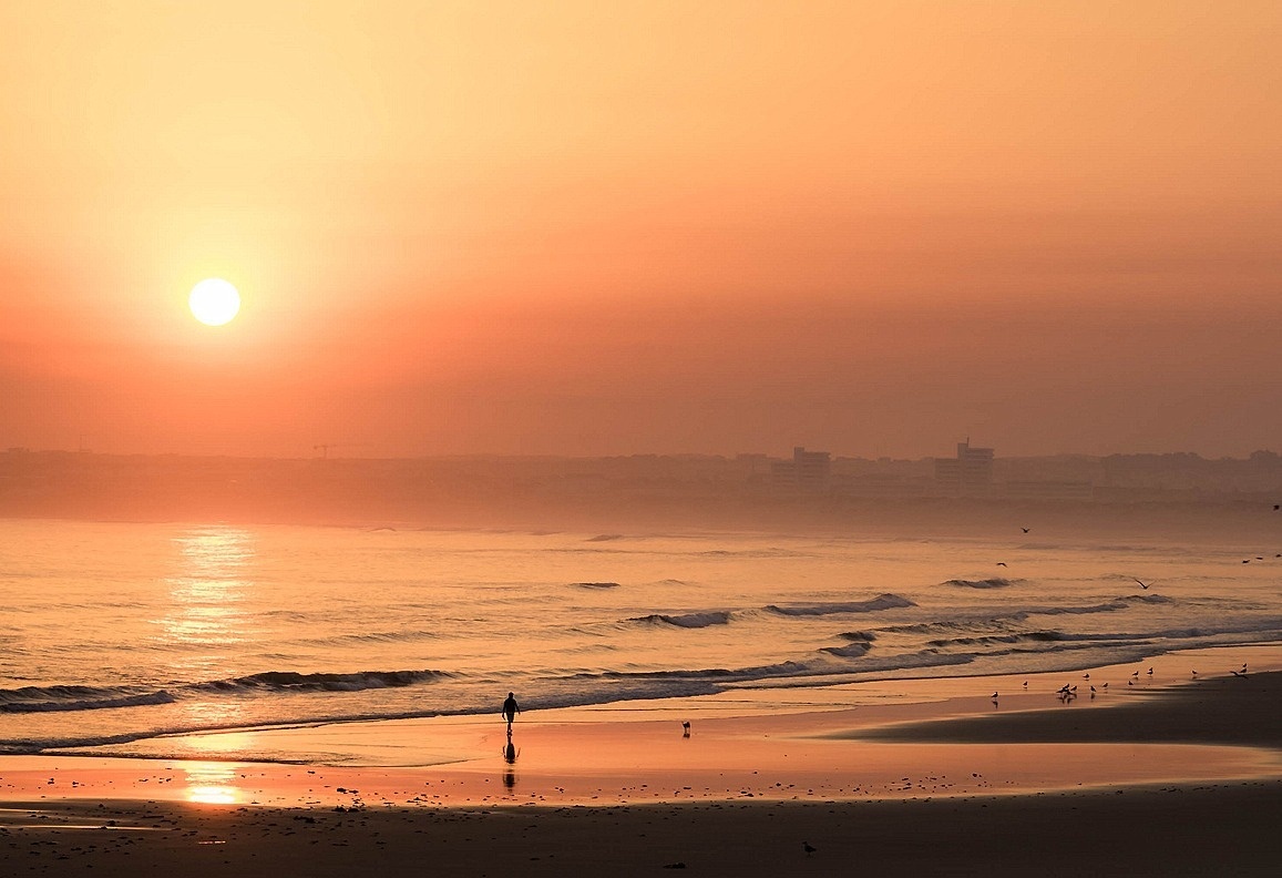 uma mulher está ao lado de uma ponte de pedra sobre o oceano