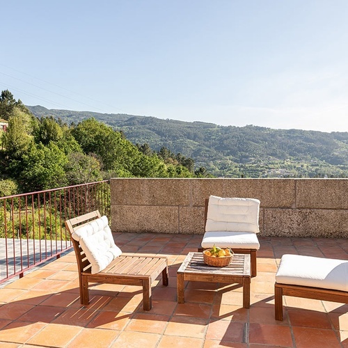 uma fileira de espreguiçadeiras com guarda-chuvas em frente a uma casa de madeira