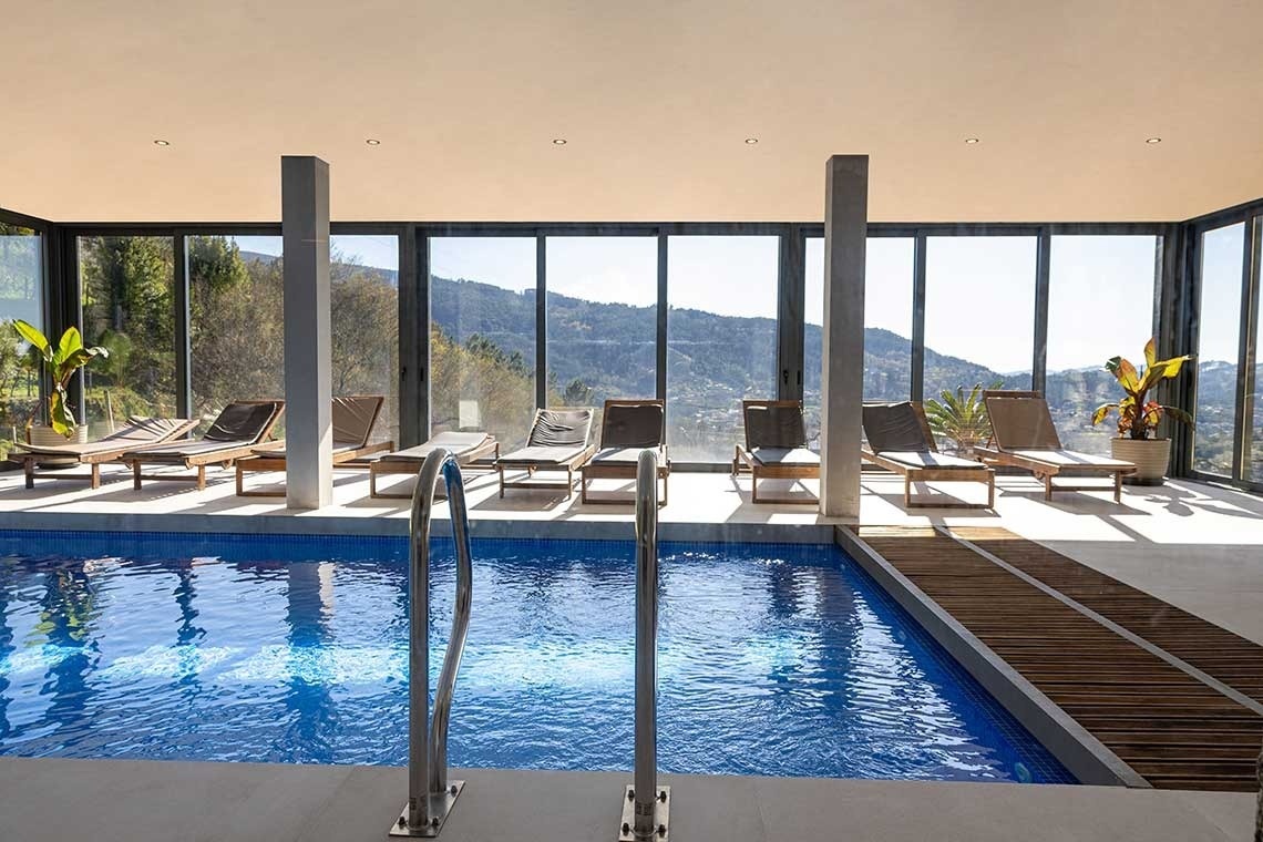 uma grande piscina azul está dentro de uma casa com muitas janelas