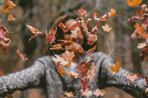 a woman is throwing leaves in the air