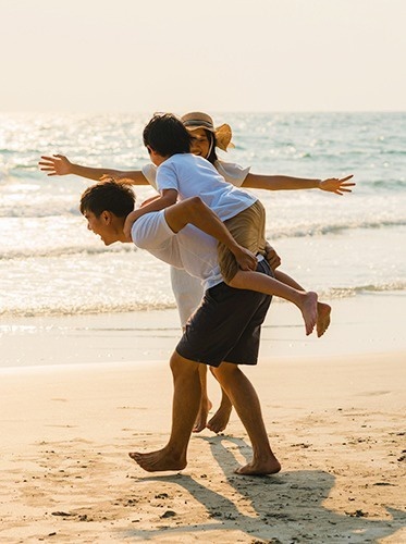a man is carrying two children on his shoulders on the beach