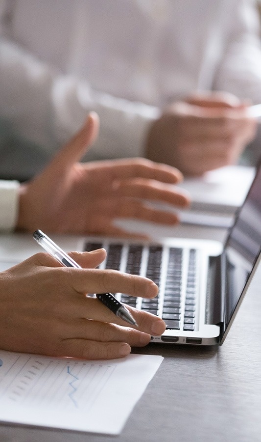 a person holding a pen in front of a laptop