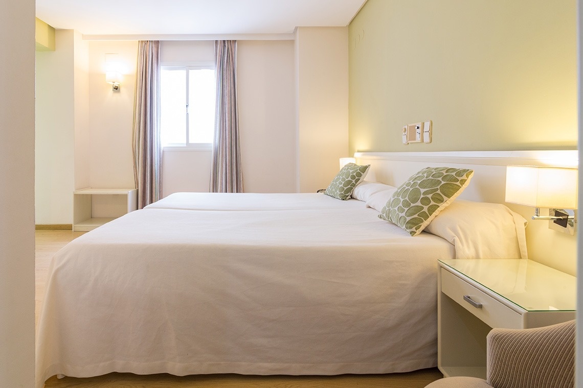 una habitación con una cama y una puerta de vidrio que conduce a un balcón