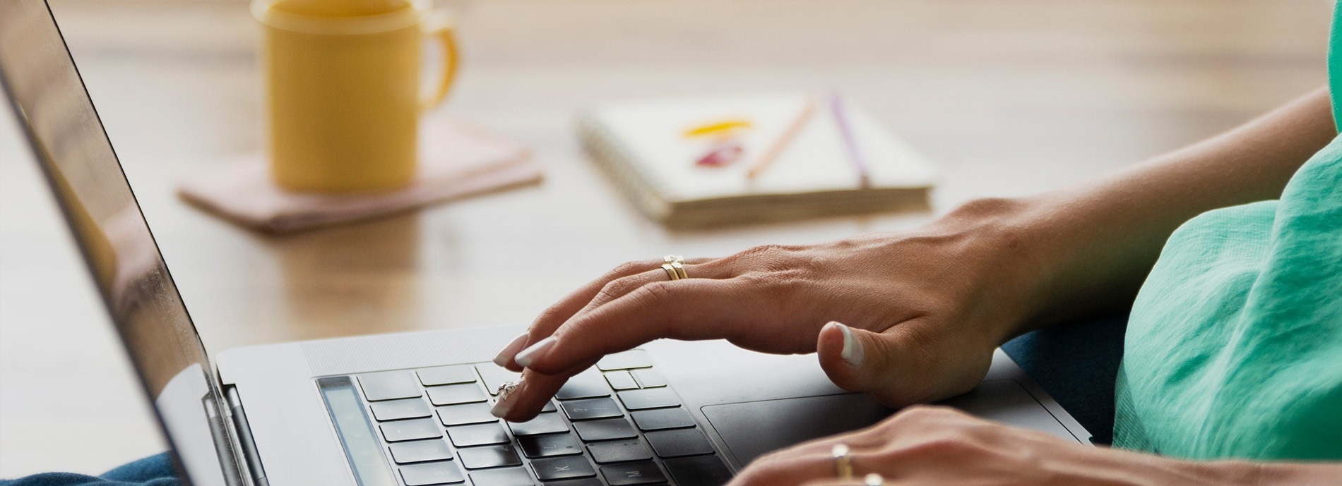 una persona está escribiendo en una computadora portátil con un anillo en el dedo índice