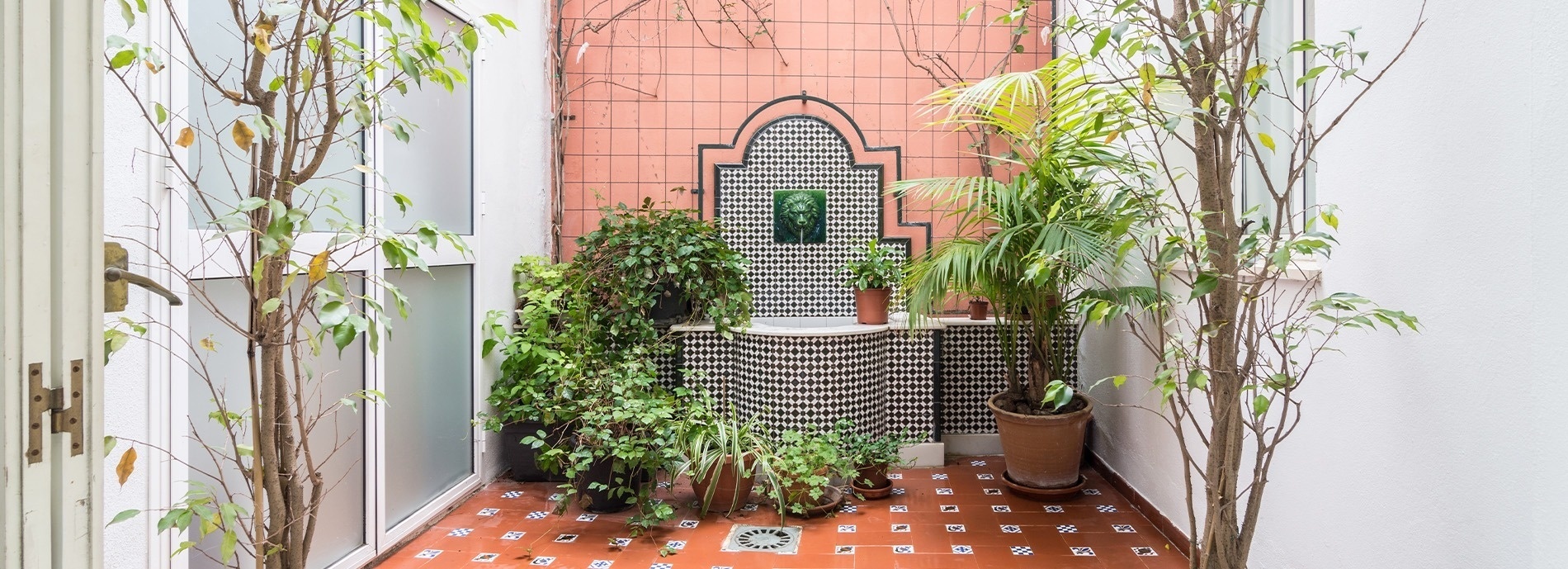 un pequeño patio con muchas plantas y un lavabo