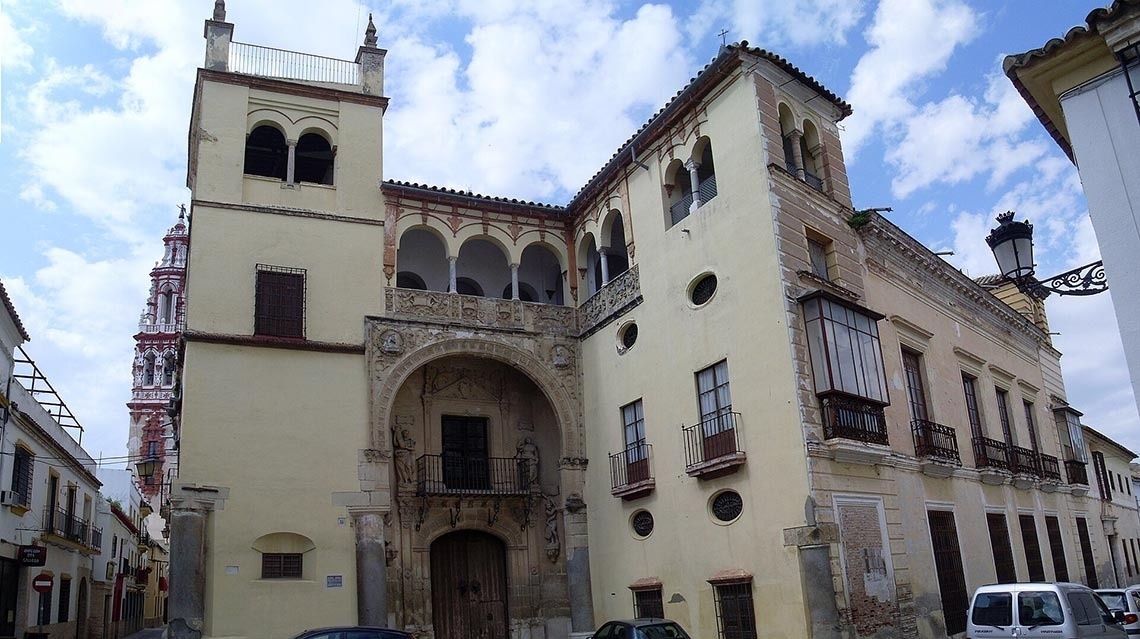un edificio amarillo con balcones y una torre en el fondo