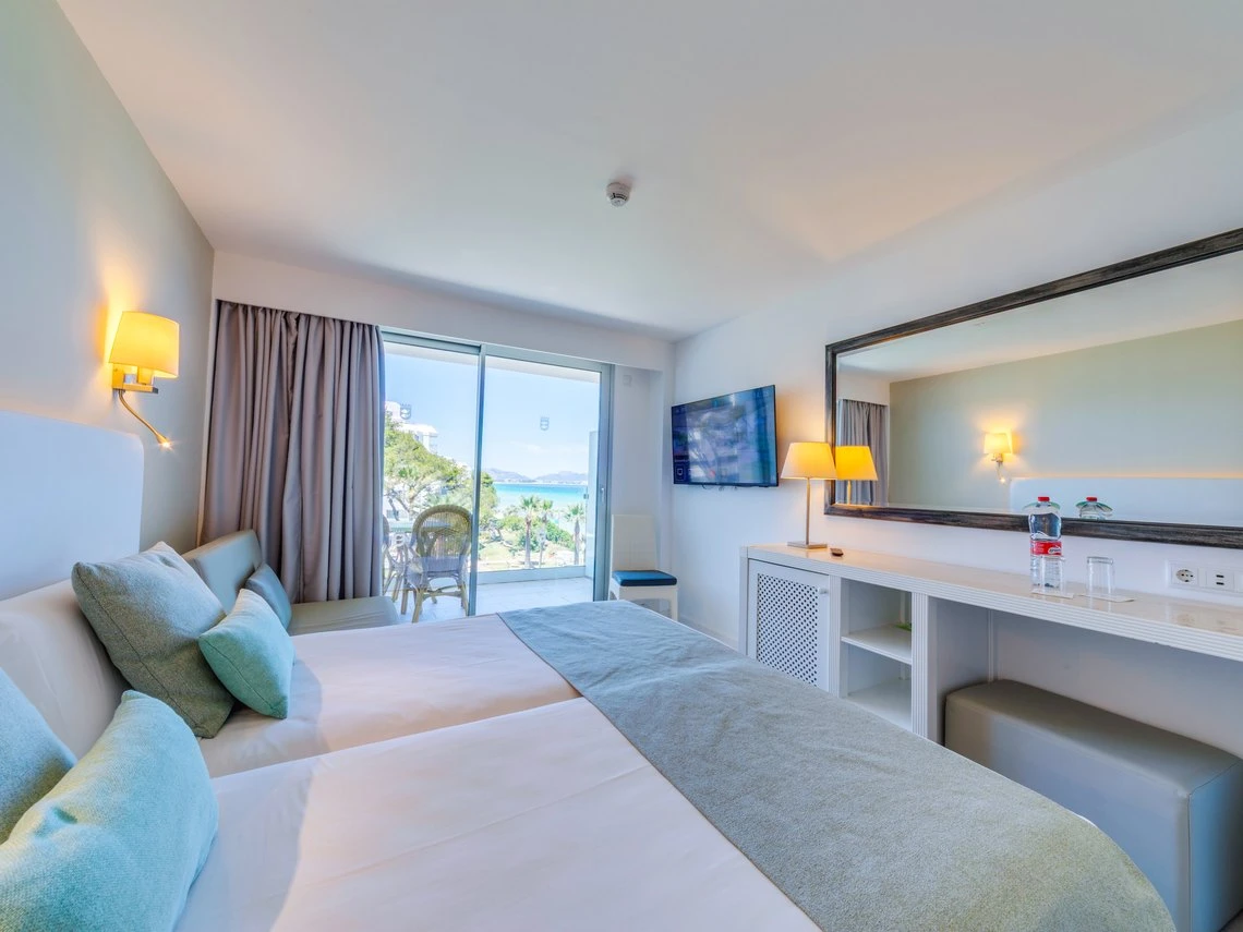 Habitación de hotel con vista al mar, camas dobles, espejo grande y balcón con Playa Esperanza Resort