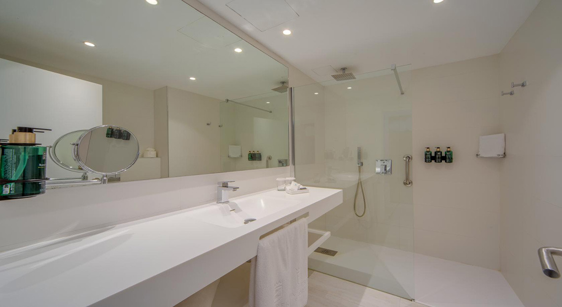 Baño moderno con ducha y lavabo. Playa Esperanza Resort en hotel.