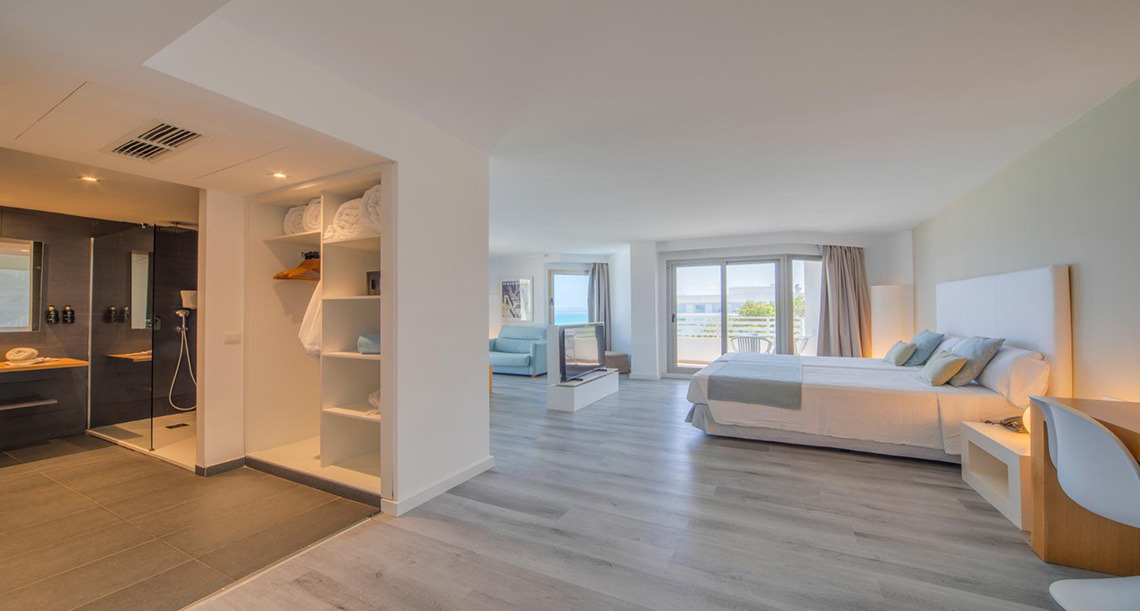 Amplia y luminosa suite de hotel con cama doble, baño moderno y balcón Playa Esperanza Resort.