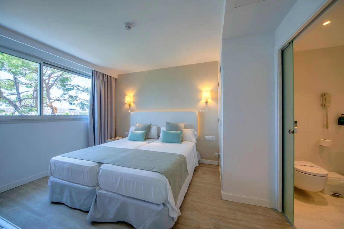 Cama doble moderna en Playa Esperanza Resort con baño adjunto.
