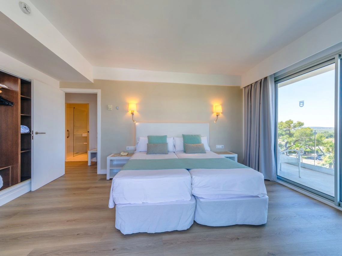 Habitación de hotel con dos camas, balcón con vistas y closet. Playa Esperanza Resort.