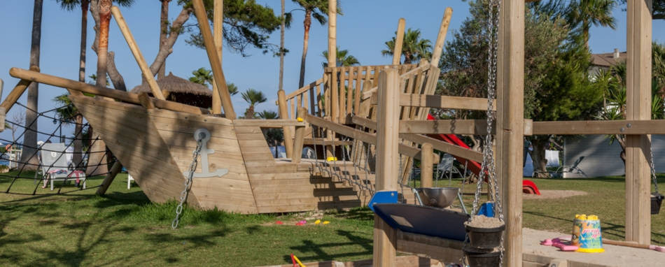 Parque infantil de madera con forma de barco, tobogán y columpio enPlaya Esperanza Resort.