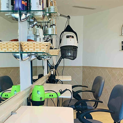 Estilizado salón de peluquería con secador de casco, secador de pelo verde y sillas para clientes, ideal para Playa Esperanza Resort.