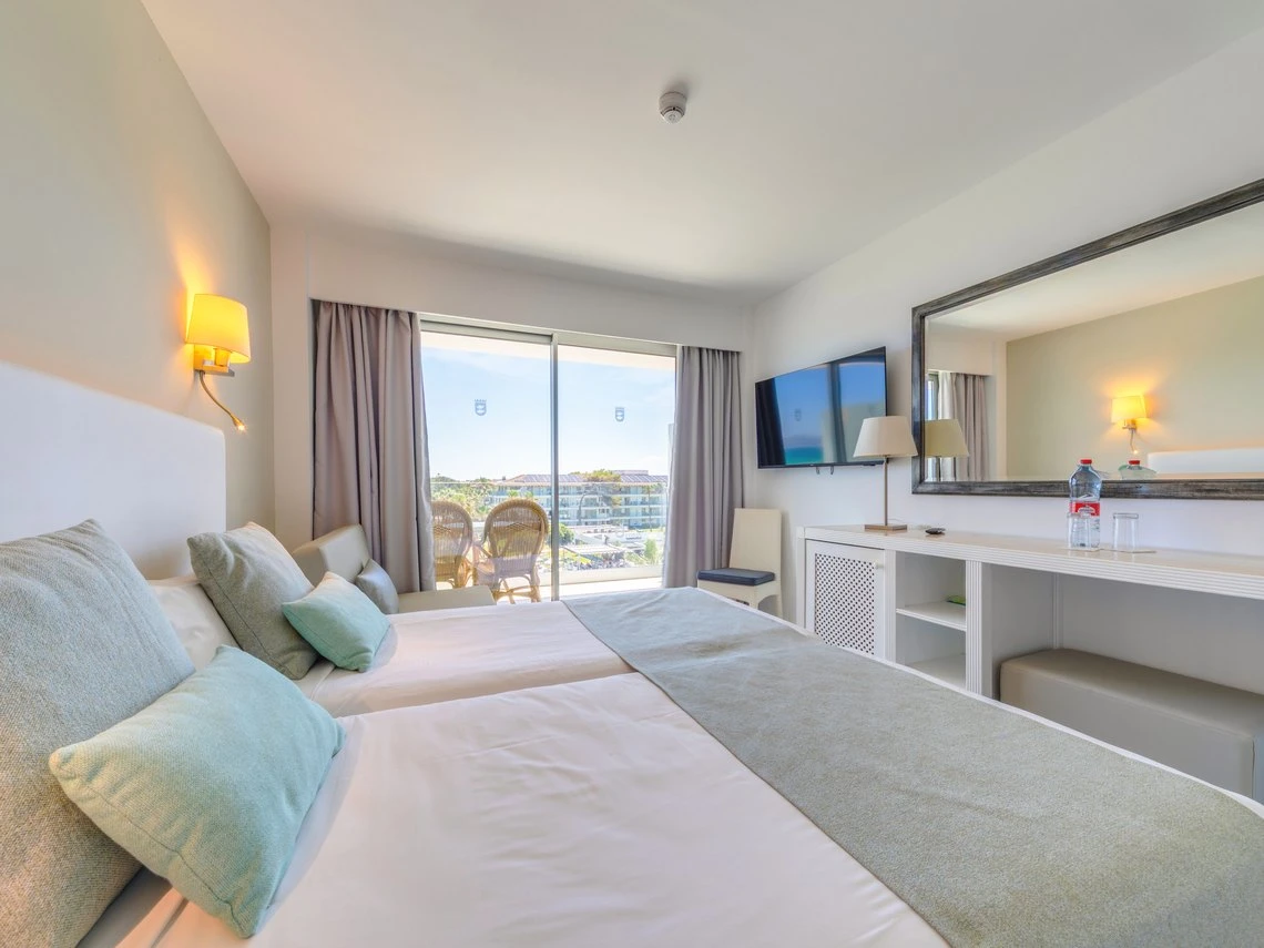 Habitación de hotel moderna con dos camas, balcón y TV. Playa Esperanza Resort