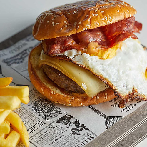 Hamburguesa con huevo frito y tocino, papas fritas. Comida de hotel Playa Esperanza Resort.