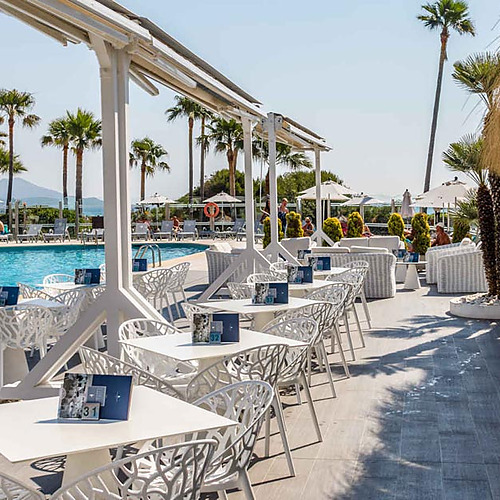 Terraza del hotel con mesas y sillas junto a la piscina, ideal para Playa Esperanza Resort.