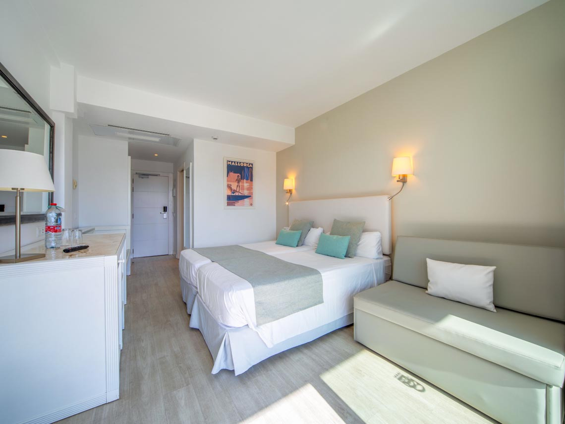 Habitación de hotel con cama doble, sofá y decoración de Playa Esperanza Resort.