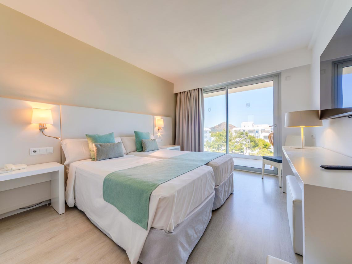 Habitación con dos camas, ventana grande con vistas y Playa Esperanza Resort.