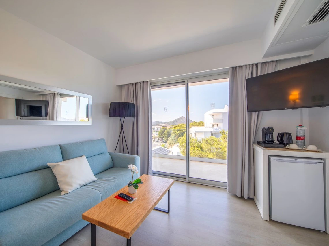Sofá azul, mesa de madera y TV en esta habitación de Playa Esperanza Resort.