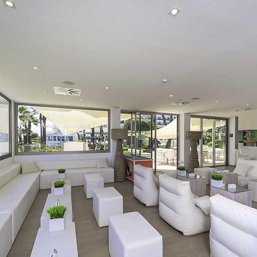 Lounge moderno del hotel con vista mar y sofás blancos, ideal para Playa Esperanza Resort.