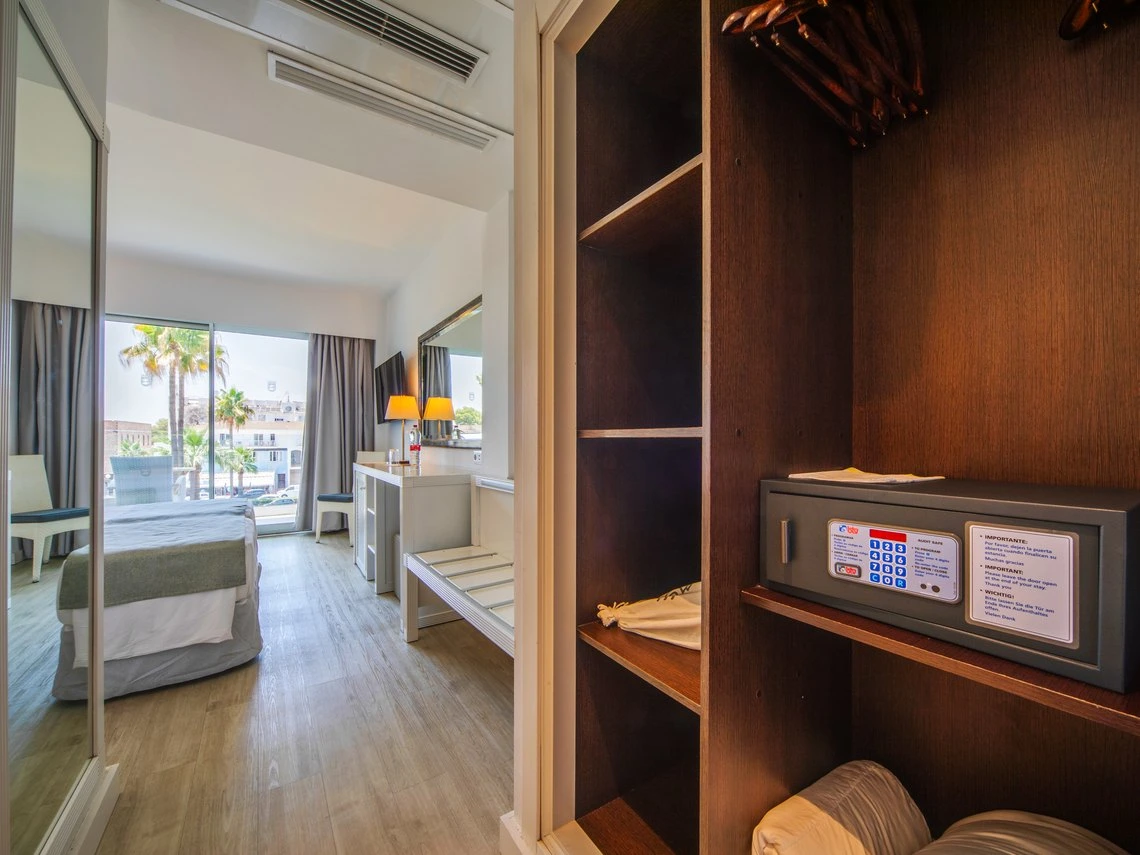 Armario con caja fuerte y perchero en habitación de hotel con cama y ventana. Playa Esperanza Resort