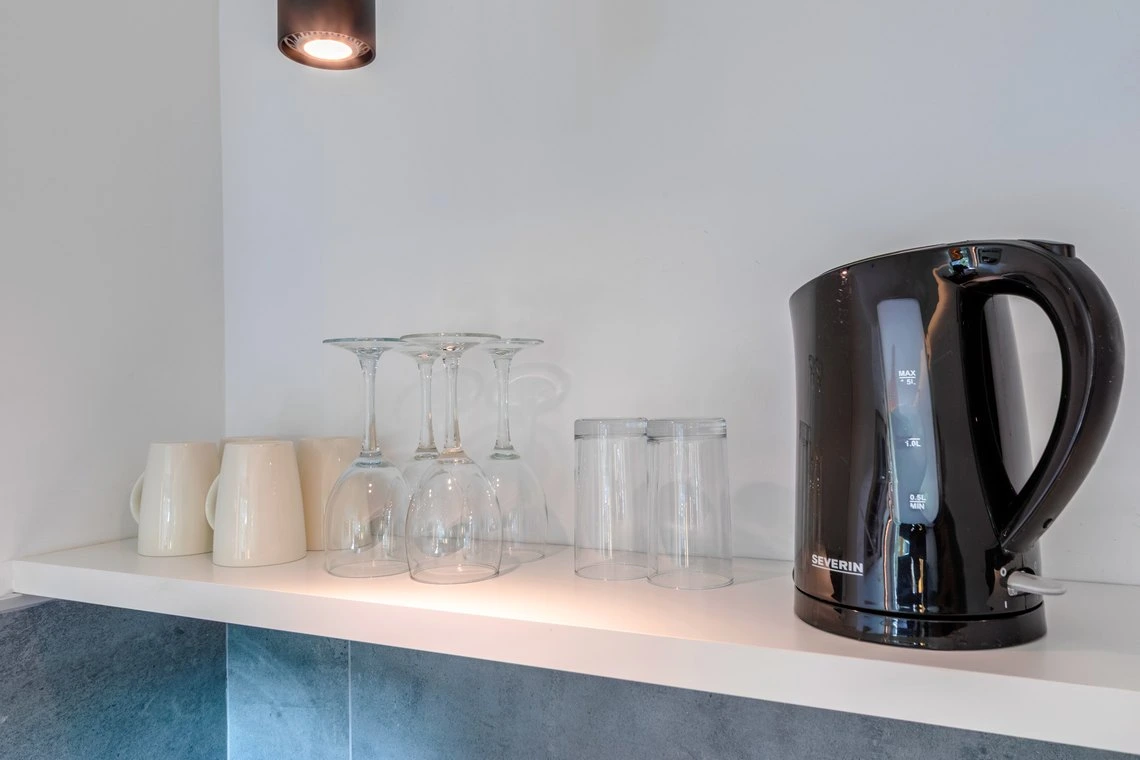 Teteras y vasos en una estantería de hotel, perfectos para tu Playa Esperanza Resort.
