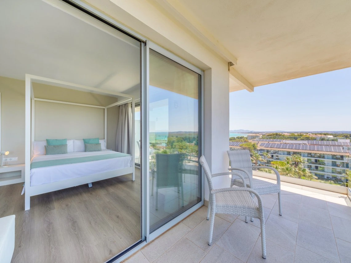 Cama con dosel en habitación de hotel con vista al mar y balcón con Playa Esperanza Resort.