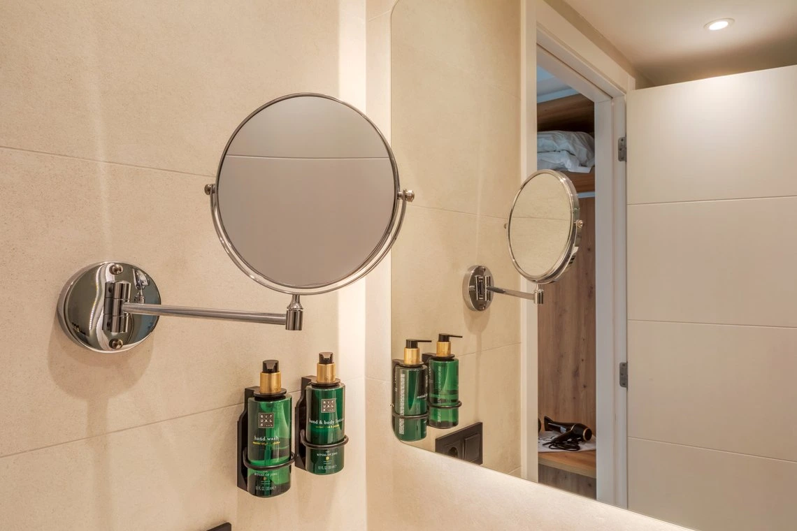 Espejo de aumento con dosificador para manos en baño de hotel con Playa Esperanza Resort.