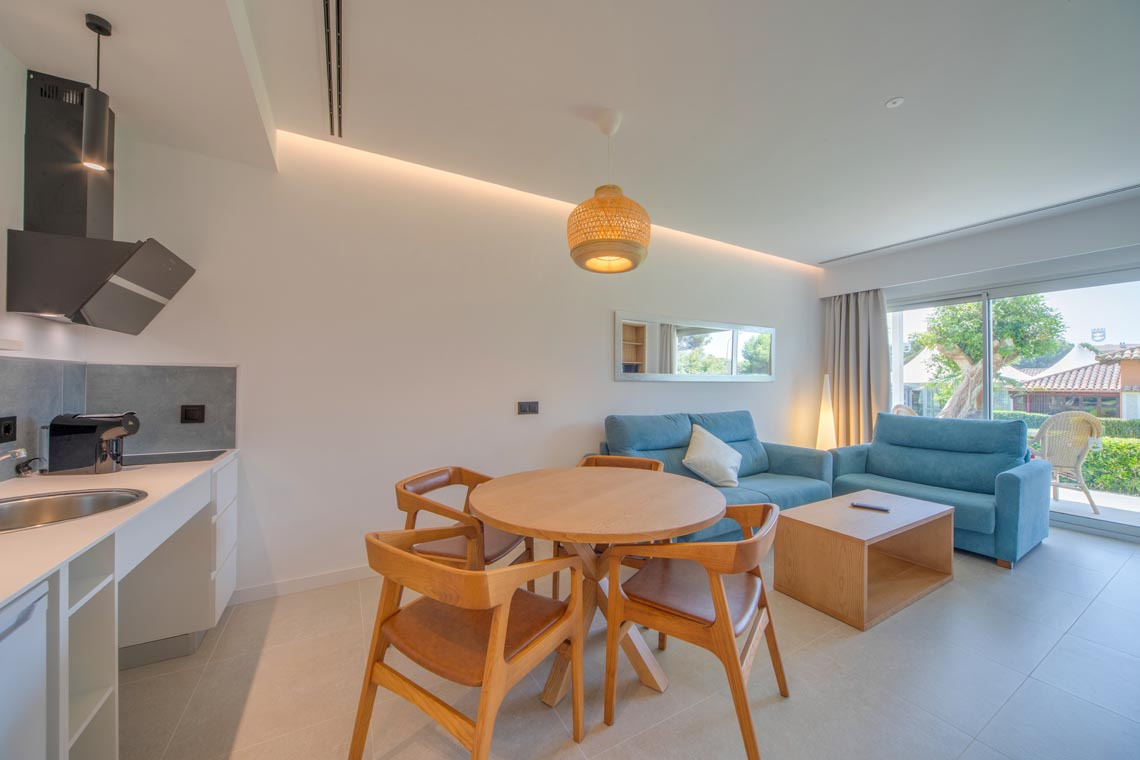 Playa Esperanza Resort: Sala de estar y comedor con sofá azul y mesa de madera.