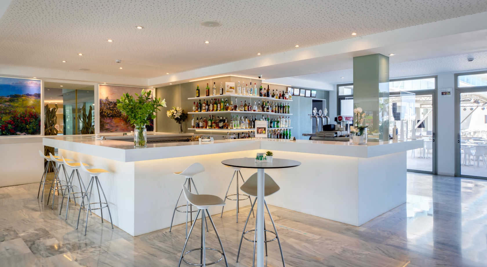 Bar moderno de hotel con estanterías de bebidas y mesas altas, ideal para Playa Esperanza Resort.