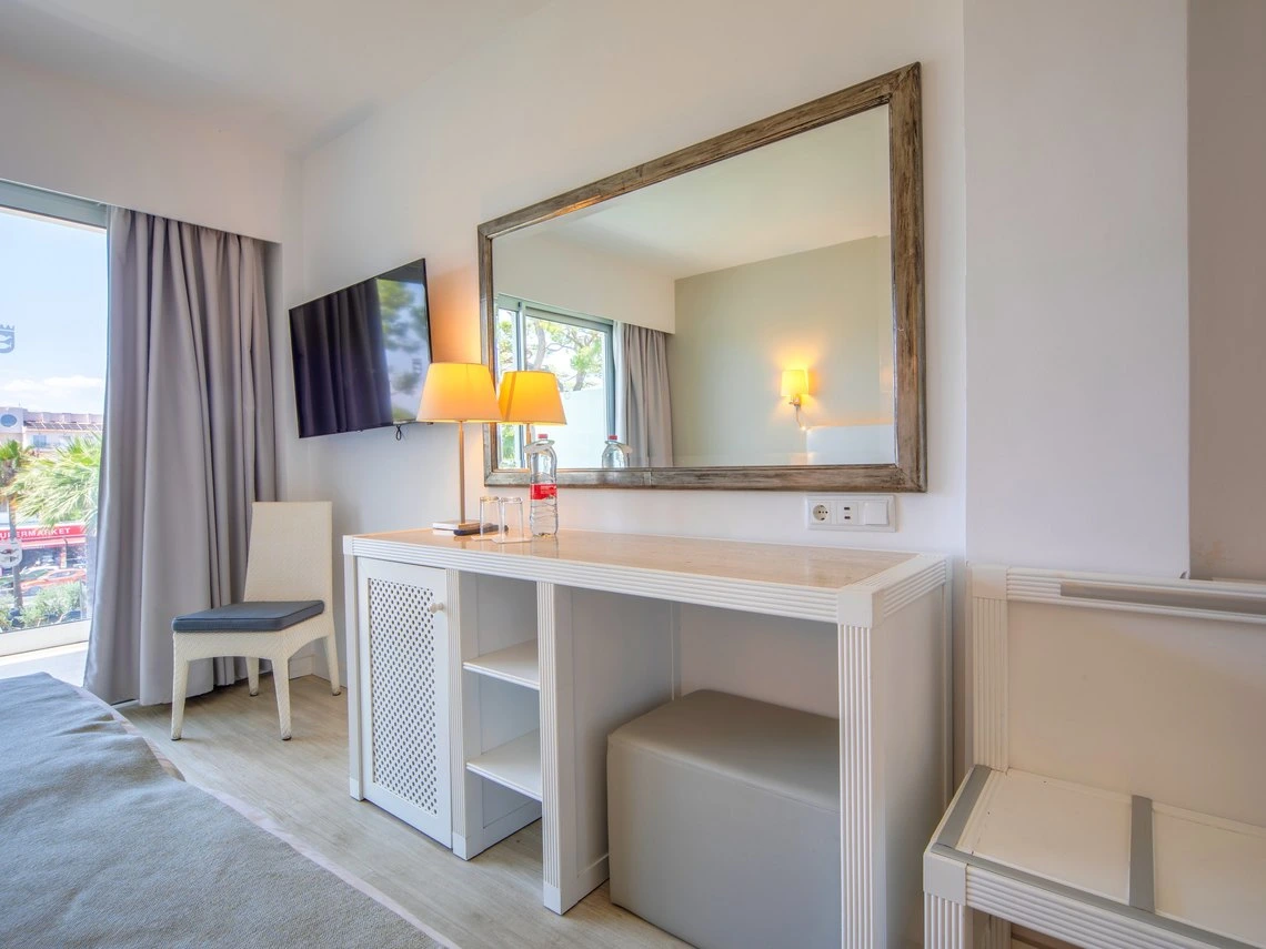 Habitación de hotel con tocador, espejo y Playa Esperanza Resort en el balcón.