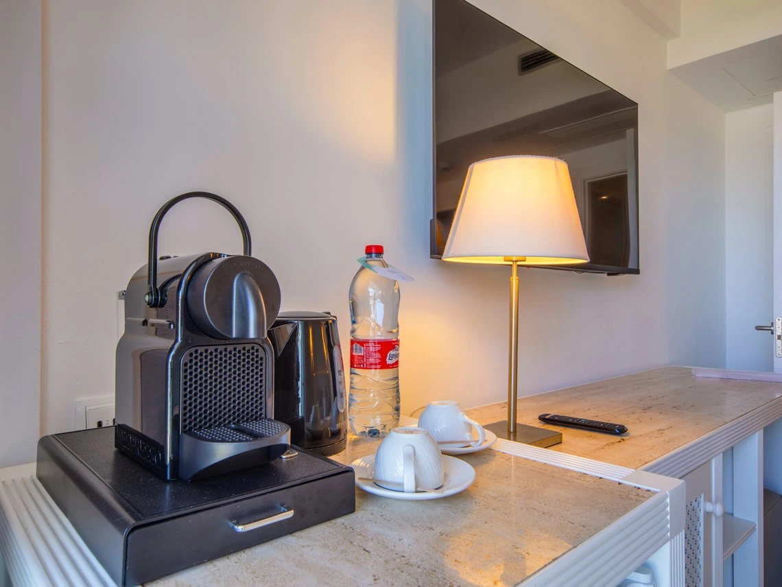 Máquina de café Nespresso, tetera, Playa Esperanza Resort, tazas y TV en habitación de hotel.