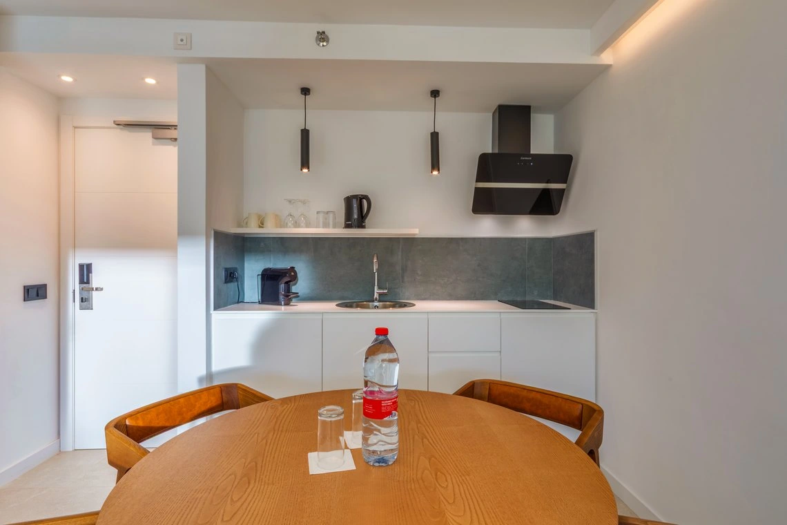 Cocina y comedor de hotel moderno con cafetera, campana extractora y mesa de madera. Playa Esperanza Resort