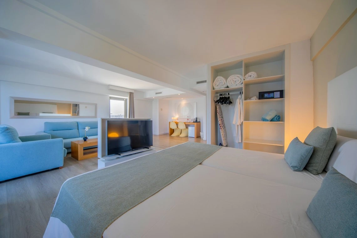 Suite de hotel moderna con sala de estar, cama doble y armario. Playa Esperanza Resort para unas vacaciones inolvidables.