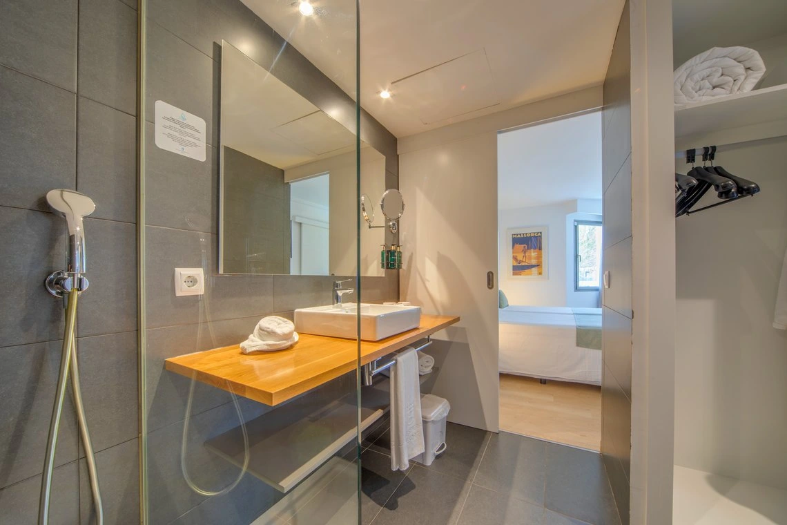 Baño moderno con ducha, lavabo, espejo y armario en habitación de hotel Playa Esperanza Resort.