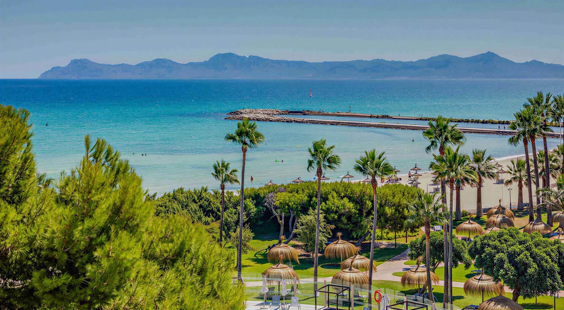 Vista aérea de hotel en la playa Playa Esperanza Resort con aguas turquesas y personas en paddleboards.
