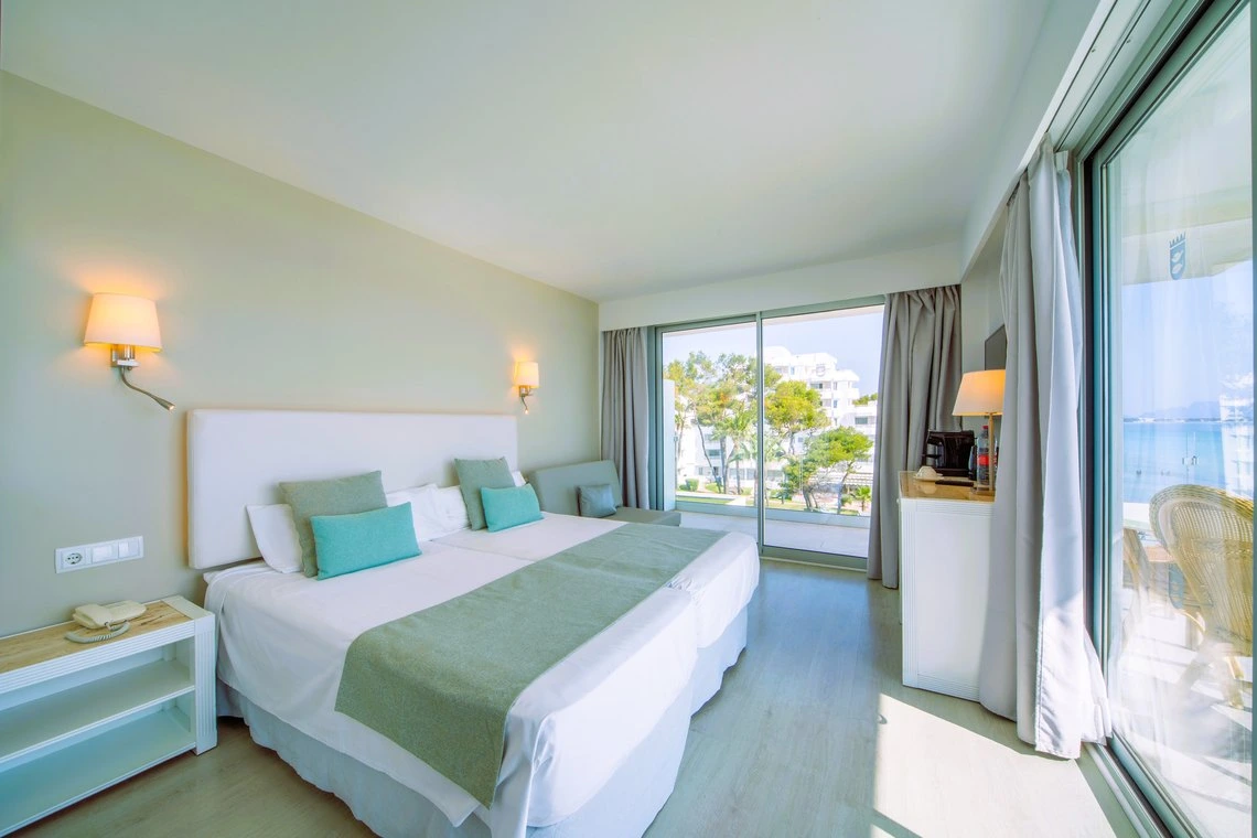 Amplia habitación de hotel con dos camas, vista al mar y balcón. Playa Esperanza Resort de lujo.