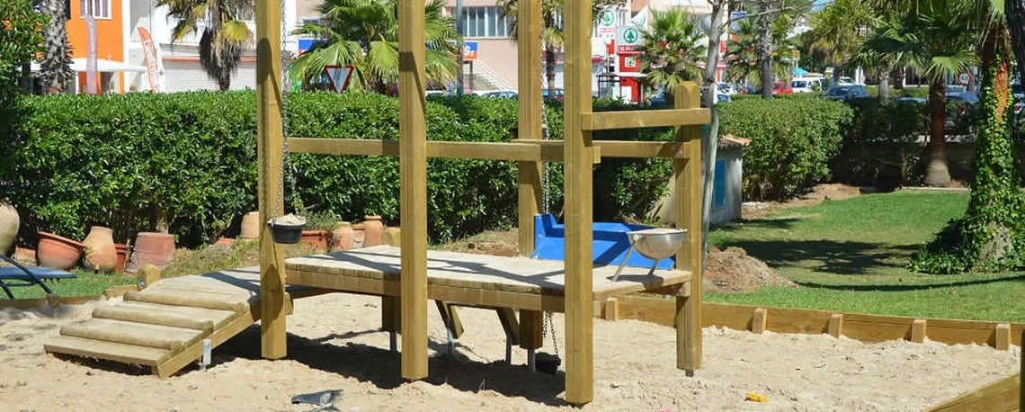 Juego de madera con arena y tobogán para niños en hotel, ideal para Playa Esperanza Resort.